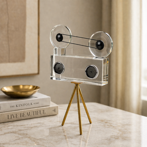 Decorative film reel sculpture on a marble surface with books and a bowl in the background.